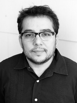 Black and white headshot of Matthew Paul Olmos, a Mexican-American man looking studious with rimmed glasses and a collar shirt with a plain background.