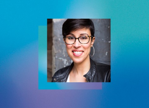 Before a teal background, a photograph of Pirronne's head and shoulders. She's in front of a concrete wall, wearing glasses, a leather jacket, and large, silver hoop earrings. She sports short, dark hair and a warm smile.