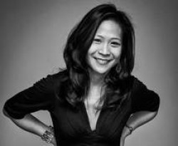 A black and white photo of director May Adrales. She is smiling.